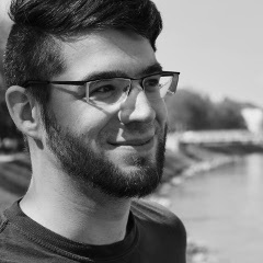 A black and white half-profile picture of Alexander Miller. He has a beard and wears glasses.
